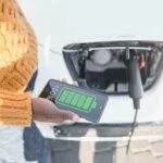 a person holding a phone with a battery on it